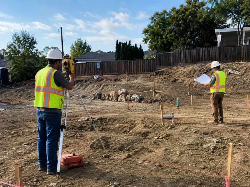 Construction Staking Site Conditions Dadeville AL - Dadeville Land Surveying Construction staking in Dadeville AL showing surveyors marking building layout points and checking site conditions before excavation.